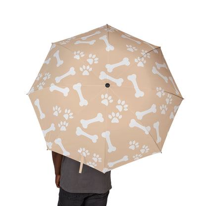 Beige umbrella with white bone and paw print pattern held by a person on a white background