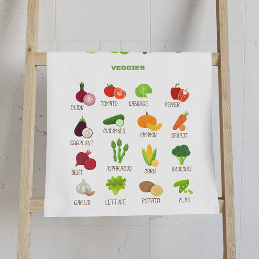 Tea towel with illustrations of vegetables on a wooden ladder against a white wall.