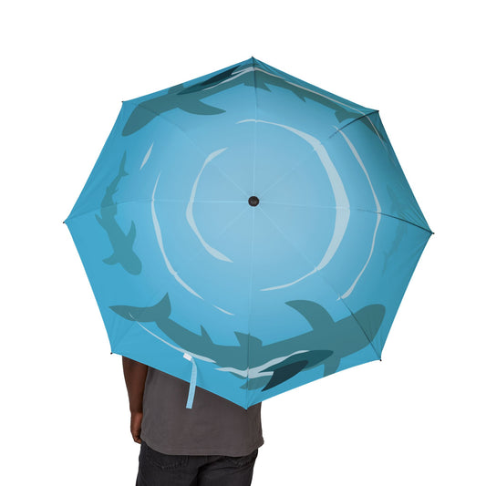 Blue umbrella with shark design held by a person on a white background